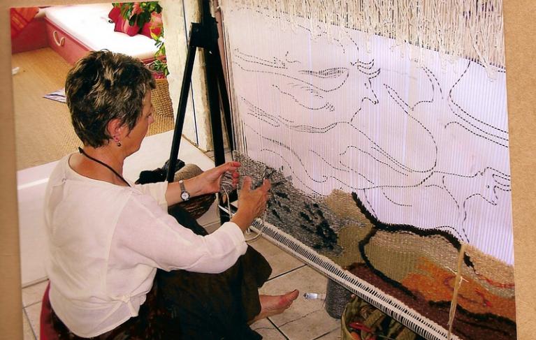 Aline Jegonday tissant une grande tapisserie de haute lice sur son métier vertical
