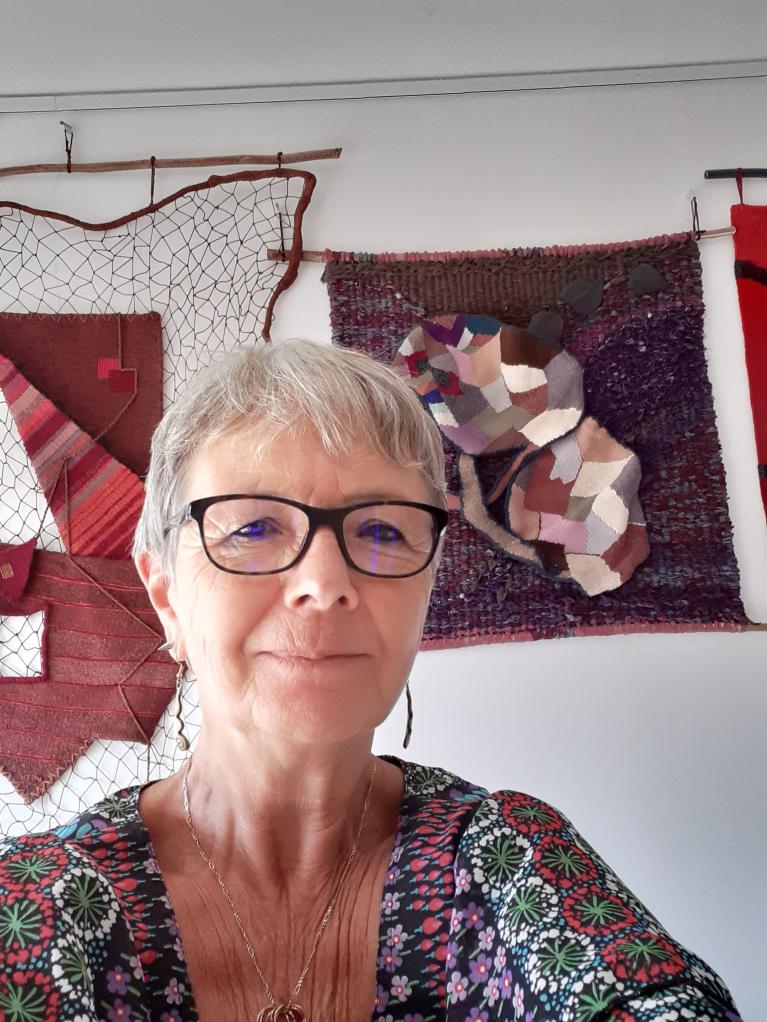 Aline Jegonday, licière, devant trois de ses tapisseries
